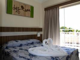 Quarto com cama de casal e sobre a cama toalhas decorativas dobradas em forma de cisnes.